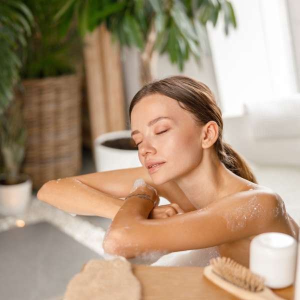 relaxed-young-woman-leaning-on-bathtub-side-while-bathing-with-eyes-closed-at-spa-resort.jpg