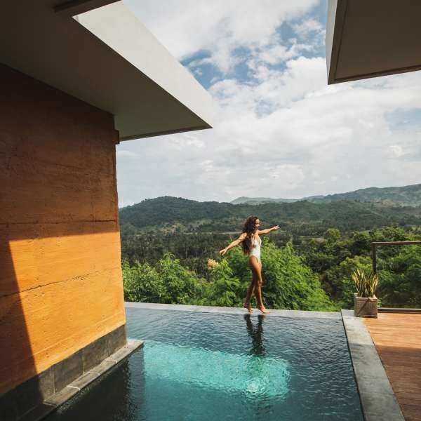 slim-beautiful-woman-in-white-swimsuit-walking-by-edge-of-infinity-swimming-pool-with-amazing-jungle.jpg